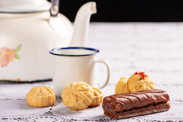 Coffee table, a beautiful coffee table with small cookies, a sweet and utensils on a lace tablecloth, dark background, selective focus.