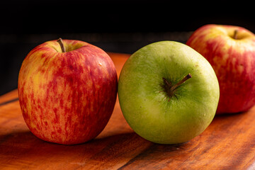 Apples, green and red apples positioned on rustic wood, dark background, selective focus.