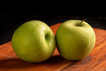 Apples, green apples positioned on rustic wood, dark background, selective focus.