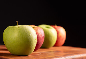 Apples, green and red apples positioned on rustic wood, dark background, selective focus.