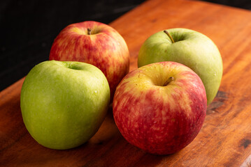 Apples, green and red apples positioned on rustic wood, dark background, selective focus.