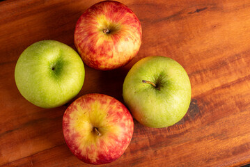 Apples, green and red apples positioned on rustic wood, dark background, top view.
