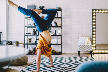 Sporty experienced young man in active wear standing on comfortable carpet