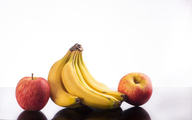 Bananas and apples, a beautiful composition with bananas and apples on a reflective surface with a light background, selective focus.