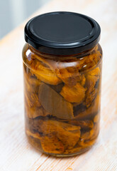 Closed glass jar with pickled red pine mushroom (lactarius deliciosus) on wooden table