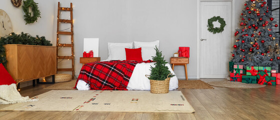 Interior of festive bedroom with Christmas tree and decorations