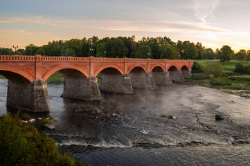 Stone bridge over Venta river next to widest waterfall in Europe-Ventas Rumba in Kuldiga, Latvia,...