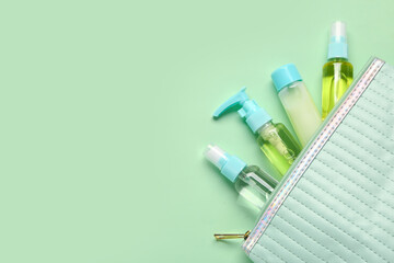 Bag with set of travel cosmetic products on green background