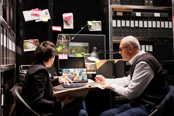 Investigators discussing with remote criminology team during online videocall, working overtime at criminal federal investigations in arhive room. Conference meeting on laptop computer display
