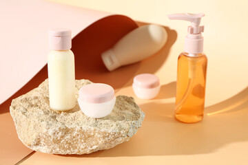 Stone with set of travel cosmetic products on color background