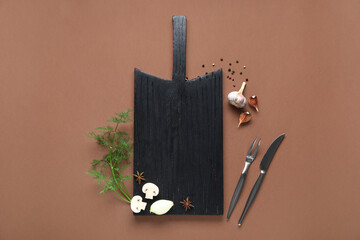 Composition with wooden cutting board, spices and cutlery on color background