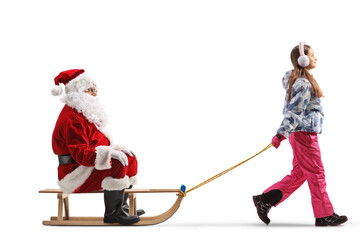Girl in winter clothes and ear muffs pulling santa claus on a sled