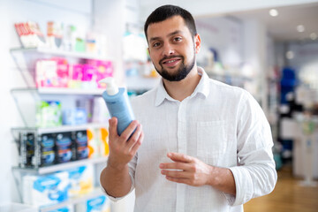 Fototapeta premium Portrait of focused bearded man choosing cosmetic product at pharmacy