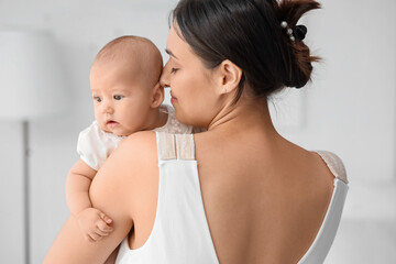 Happy mother with cute little baby in room at home