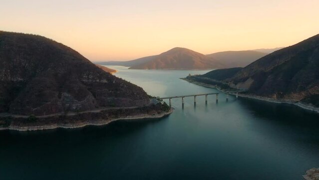 Aerial drone flying over a lake, water dam, with mountains and a bridge at sunrise. Beautifull dreamy landscape view. Coastline with boats. Pacefull landscape. Cabra Corral, Salta, Argentina.