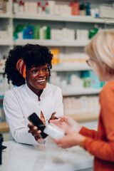 African american woman pharmacist selling drugs to a senior customer in a pharmacy