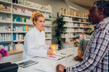 Fototapeta na wymiar Woman pharmacist selling drugs to a senior patient customer in a pharmacy