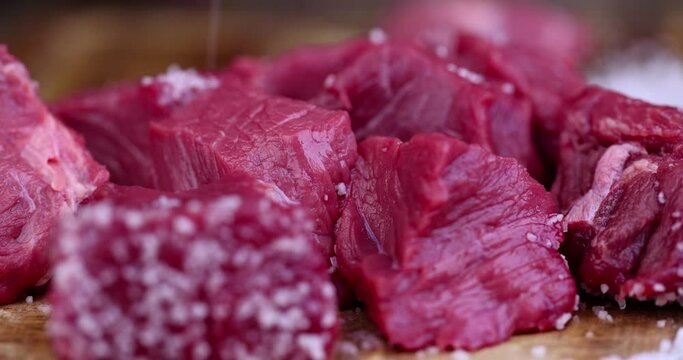 sprinkle with salt sliced piece of fresh raw beef, during salting, preparation of semi-finished products with beef meat with salt