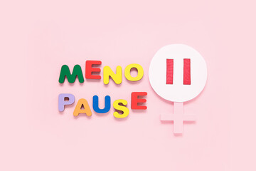 Word MENOPAUSE with symbol of woman on pink background