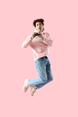 Tattooed young man with game pad jumping on pink background