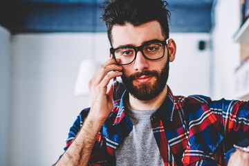 Bearded male librarian calling on modern smartphone standing in university