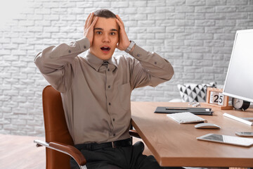 Afraid young man sitting at table in room