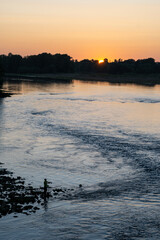 Naklejka premium Lone fisherman on bank of Loire river fishes at sunset at dusk, France