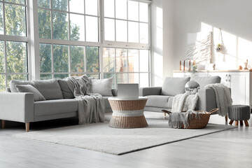 Interior of modern living room with disco ball, grey sofas and laptop on coffee table