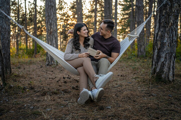 Young couple man and woman give present gift box while sit in nature