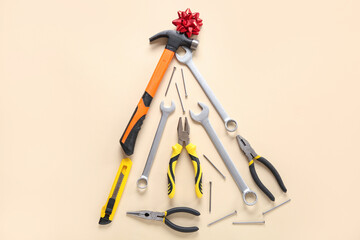Christmas tree made of repair tools and bow on beige background