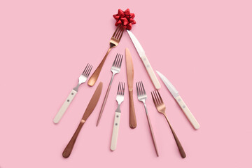 Christmas tree made of cutlery and bow on pink background