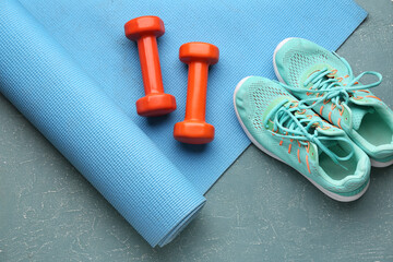 Dumbbells, yoga mat and shoes on blue