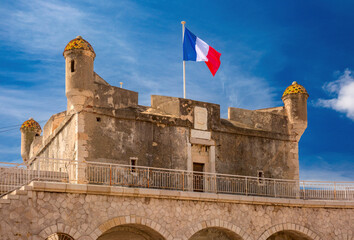 The French flag flies over Old bastion fort on the seashore in Menton, French Riviera, France
