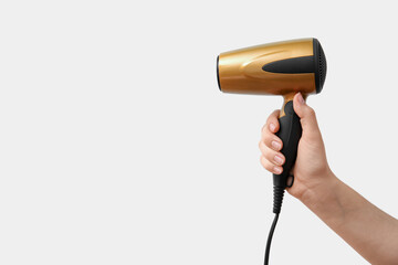 Female hand with hair dryer on grey background