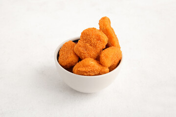 Bowl with tasty nuggets on white background