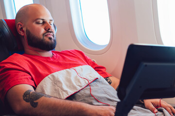 30 years old Caucasian man sleeping on wide seat cowered with blanket during business class flight time