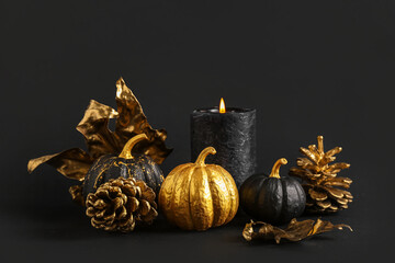 Painted pumpkins with cones, candle and leaves on black background