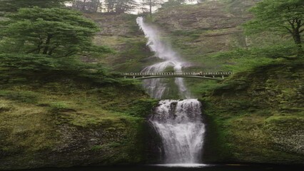 Panning shot of distant Multnomah Falls waterfall in green forest - vertical video / Bridal Veil, Oregon, United States - Powered by Adobe