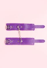 Purple handcuffs from sex shop on pink background