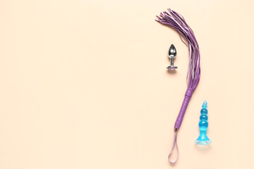 Anal plugs and whip from sex shop on pink background