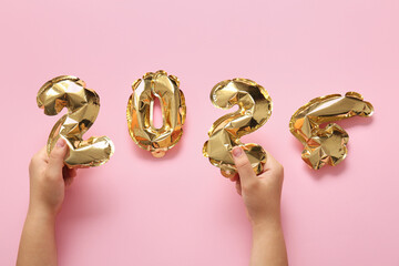 Female hands with figure 2024 made of foil balloons on pink background