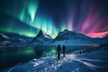 A distant photo of a group of tourist mountaineers and their guide are hiking to a rock in front of a mountain lake with thick coats on a in snow covered mountain hill with northern lights with trails - obrazy, fototapety, plakaty
