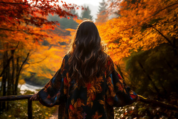 A young asian woman is posing in front of the camera from the front happily with an autumn coat in a forest during sunset in autumn in a vibrant coloration