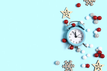 Christmas composition with alarm clock, snowflakes and baubles on blue background