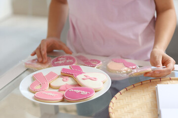 Obraz na płótnie Canvas Young woman bagging cookies at home, closeup. Breast cancer awareness concept
