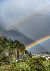Beautiful view of the rainbow over the  volcanoes in the city of Banos, Ecuador. Amazing sunset.