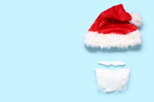 Santa hat and beard made of cotton wool on color background
