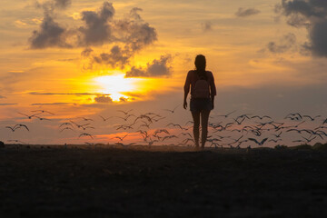 A tourist woman walking in the sunset with a backpag in Acapulco beach