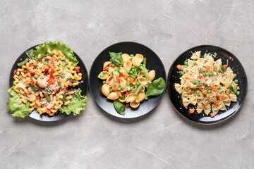 Plates with tasty pasta primavera on grey background