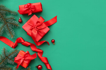 Red gift boxes with Christmas tree branches and balls on green background